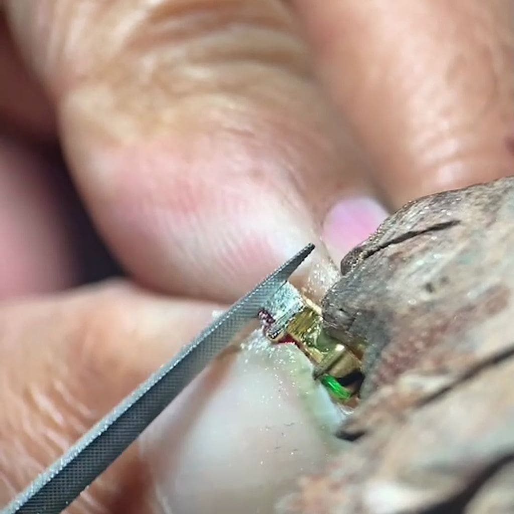 Close-up of a diamond being examined with tweezers against a wooden background Image