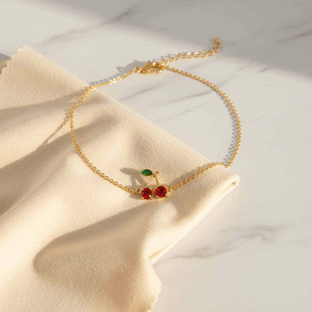 Gold necklace with cherry pendant on a beige fabric background Image