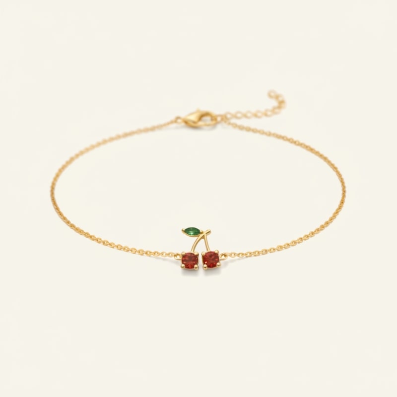 Gold bracelet with cherry-shaped charms on a white background