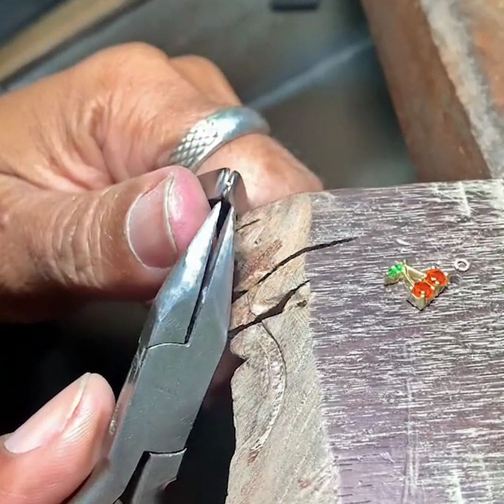 Person using pliers on a piece of wood with small decorative items nearby. Image