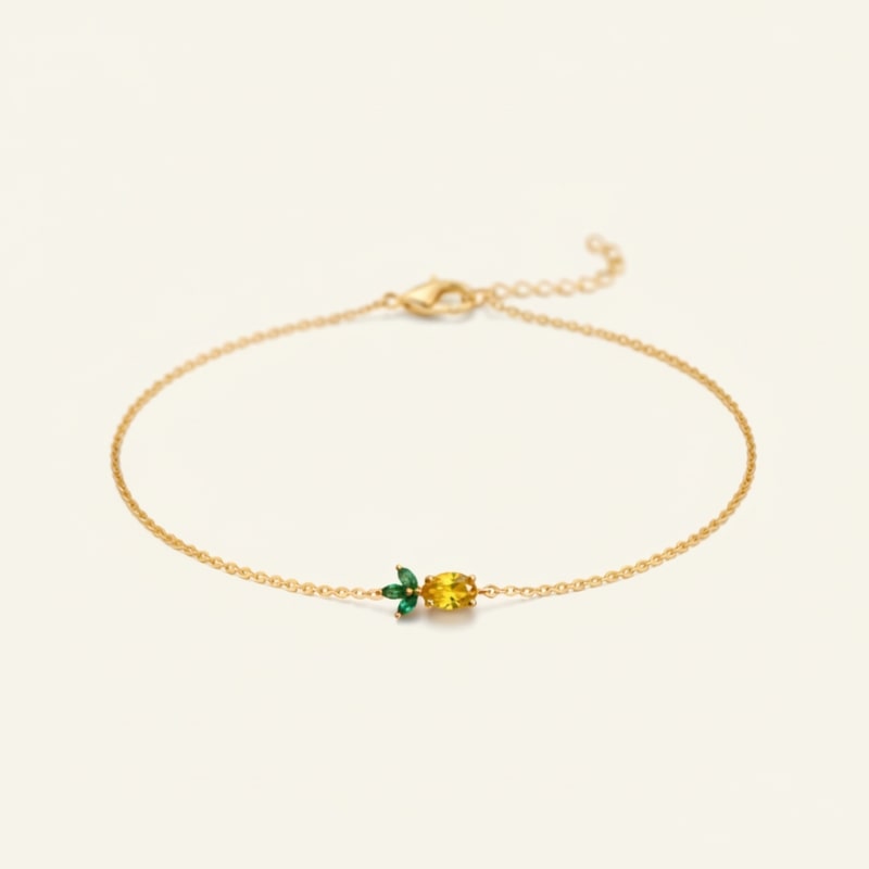 Gold bracelet with a green and yellow bead on a beige background